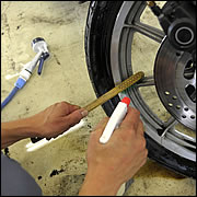 洗車は汚れの激しい足回りから。油汚れを浮かす洗浄剤を吹きかけ、ブラッシングを繰り返す。とても細かい作業だ。