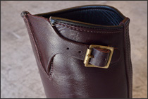 ブーツインで履くことを考えて、ふくらはぎ部のフィット感を調整できるトップストラップ。ハードウェアはインステップと同じブラス製ローラーバックル。